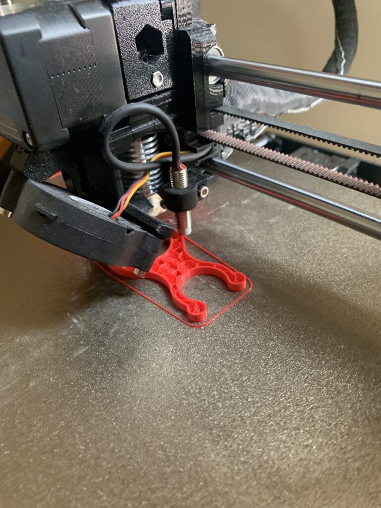 3D Printed bike pump bracket. Red. Smiley face, happy! On the printer. Prusa MK3